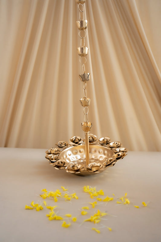 Gold decorative hanging item with yellow petals on a beige background