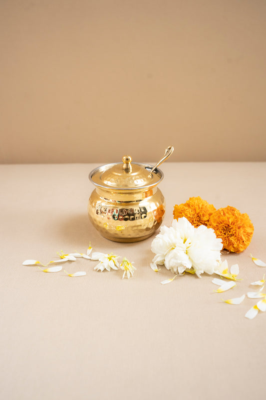 Gold decorative pot with flowers on a beige surface