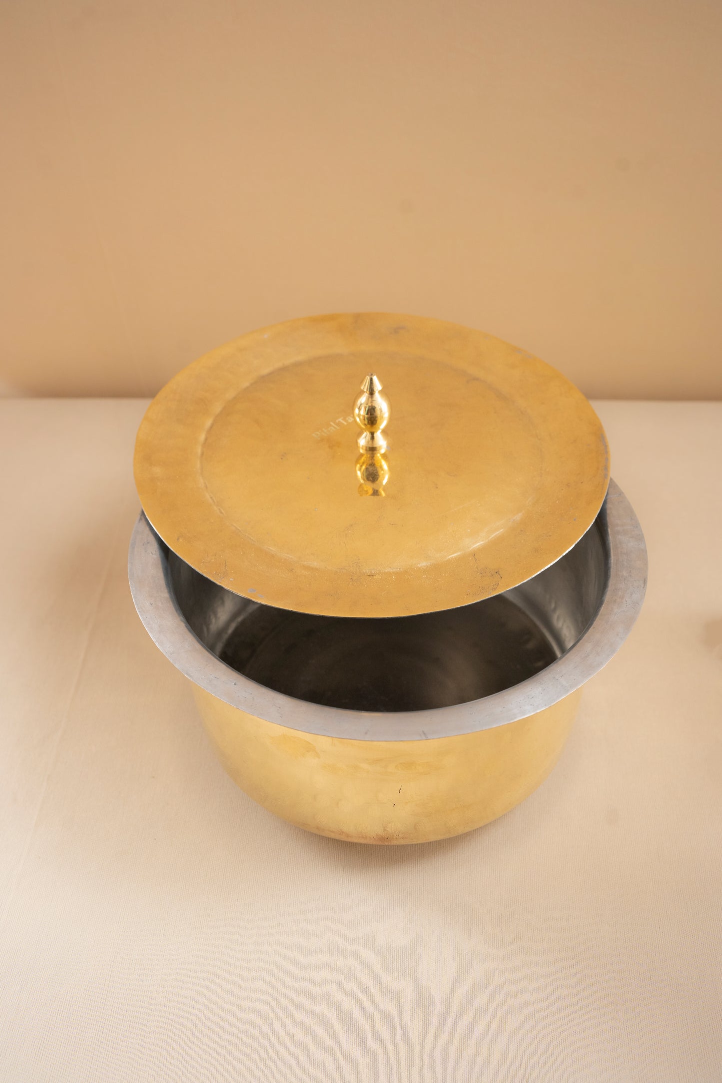 Brass pot with a lid on a beige background