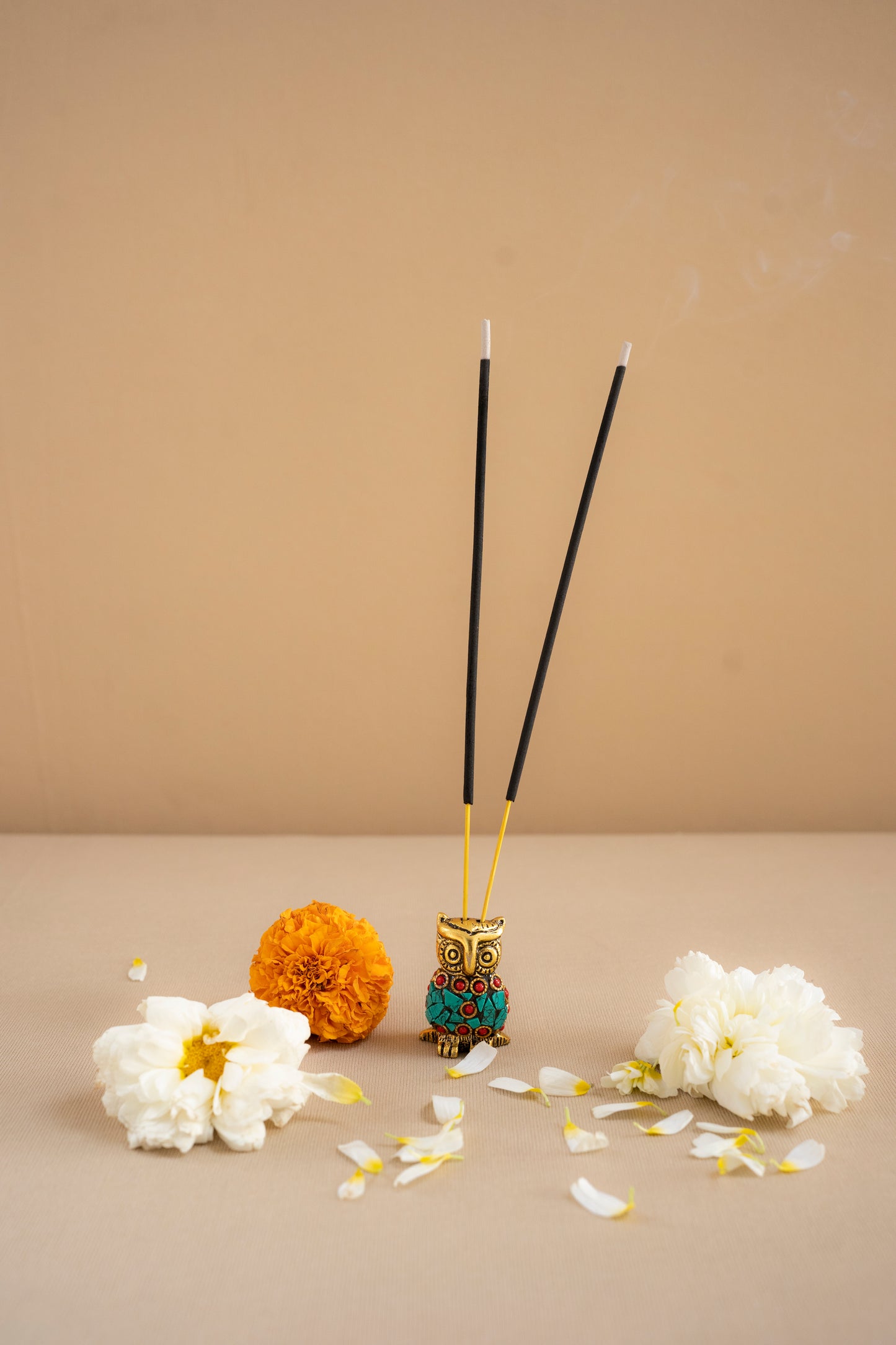 Incense sticks in a holder with flowers on a beige background