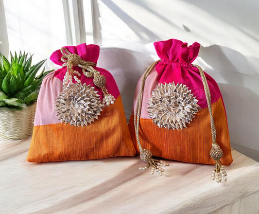 Two decorative bags with pink top and orange bottom on a light surface.