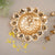 Decorative gold wall clock with floral design on a neutral background