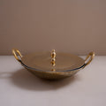 Gold decorative dish with handles on a beige surface and background