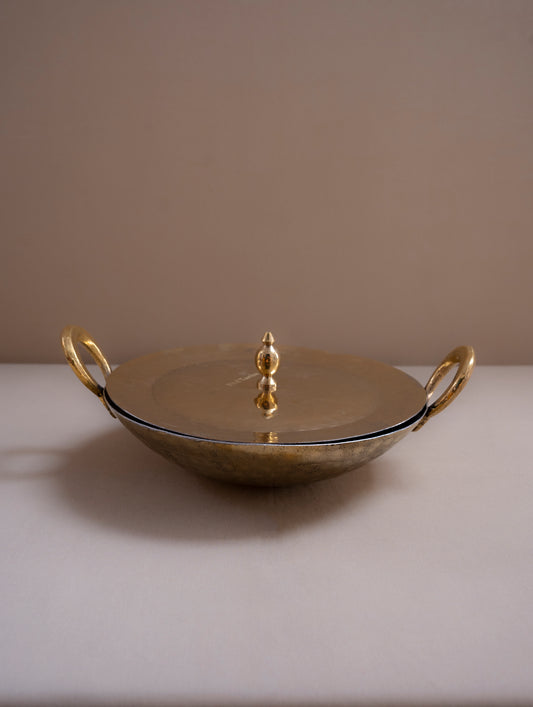 Gold decorative dish with handles on a beige surface and background