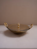 Gold decorative dish with handles on a beige surface and background