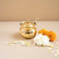 Gold decorative pot with flowers on a beige surface