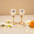 Two gold and silver goblets on a beige surface with flowers around them.