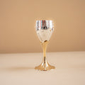 Decorative glass goblet with gold base and silver top on a beige background