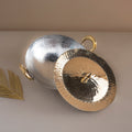 Two metallic pendants, one gold and one silver, on a neutral background.