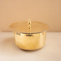 Gold metallic container with lid on a beige surface