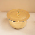 Gold-colored pot with lid on a beige background