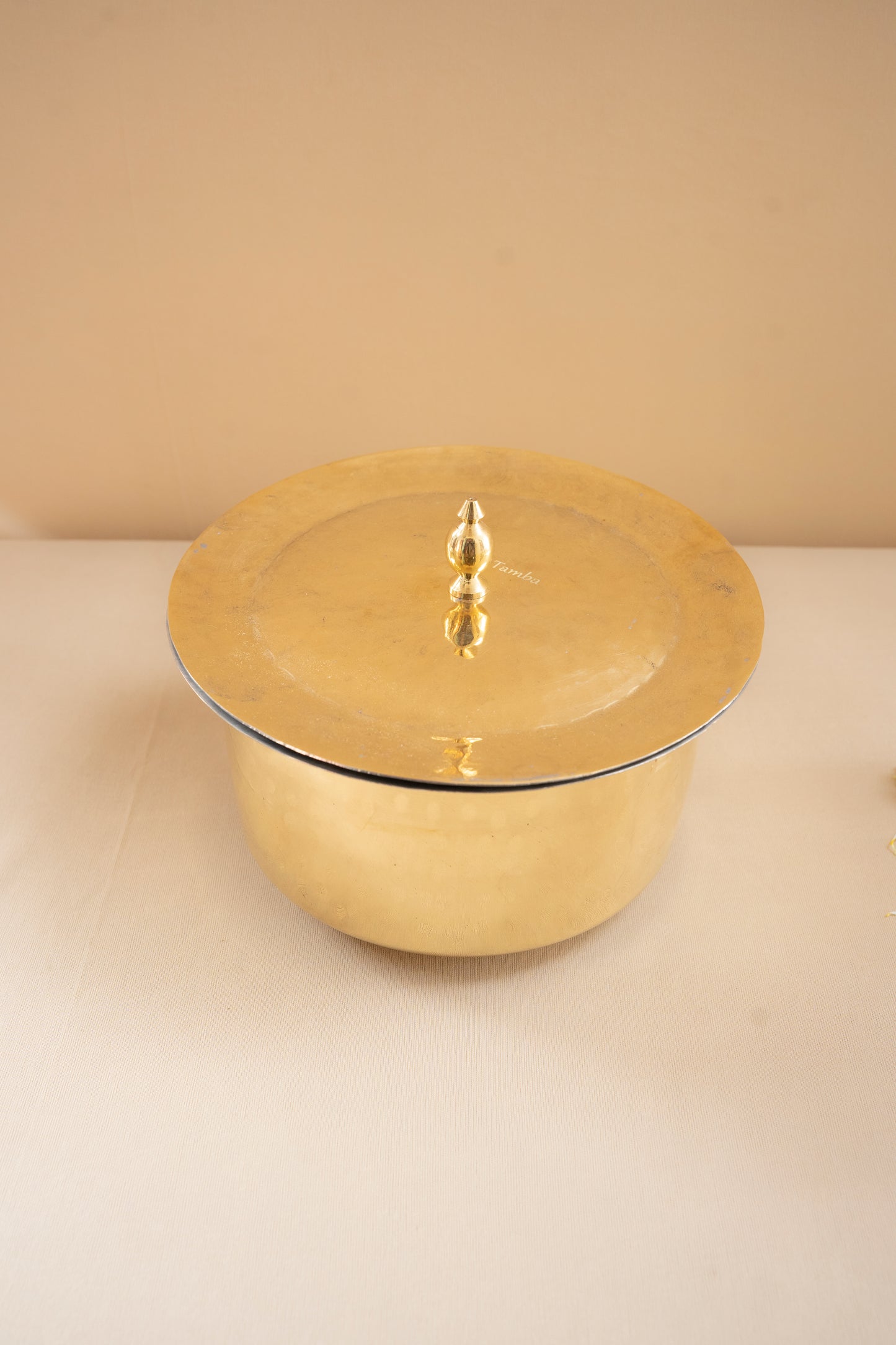 Gold-colored pot with lid on a beige background