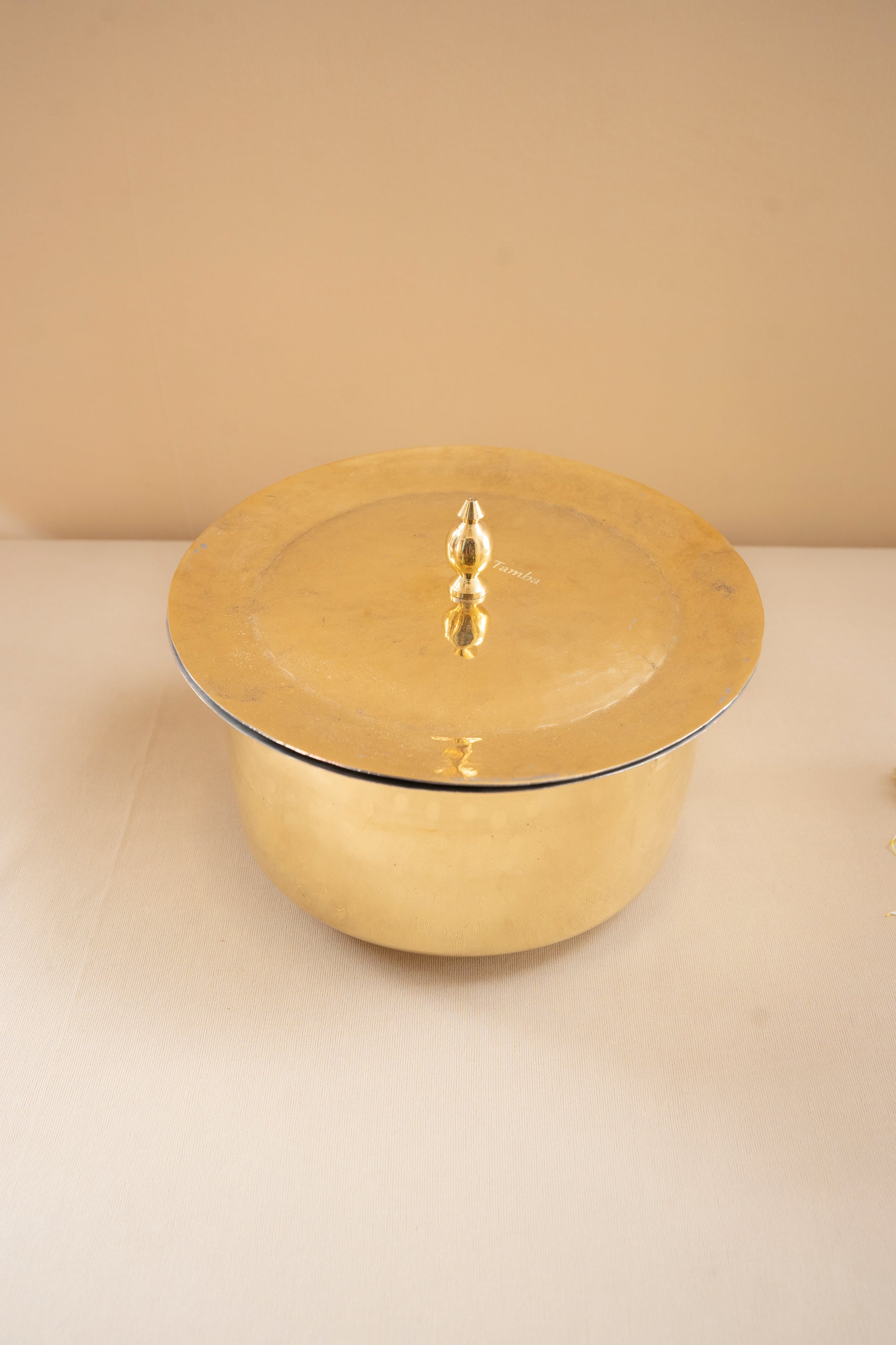 Gold-colored pot with lid on a beige background