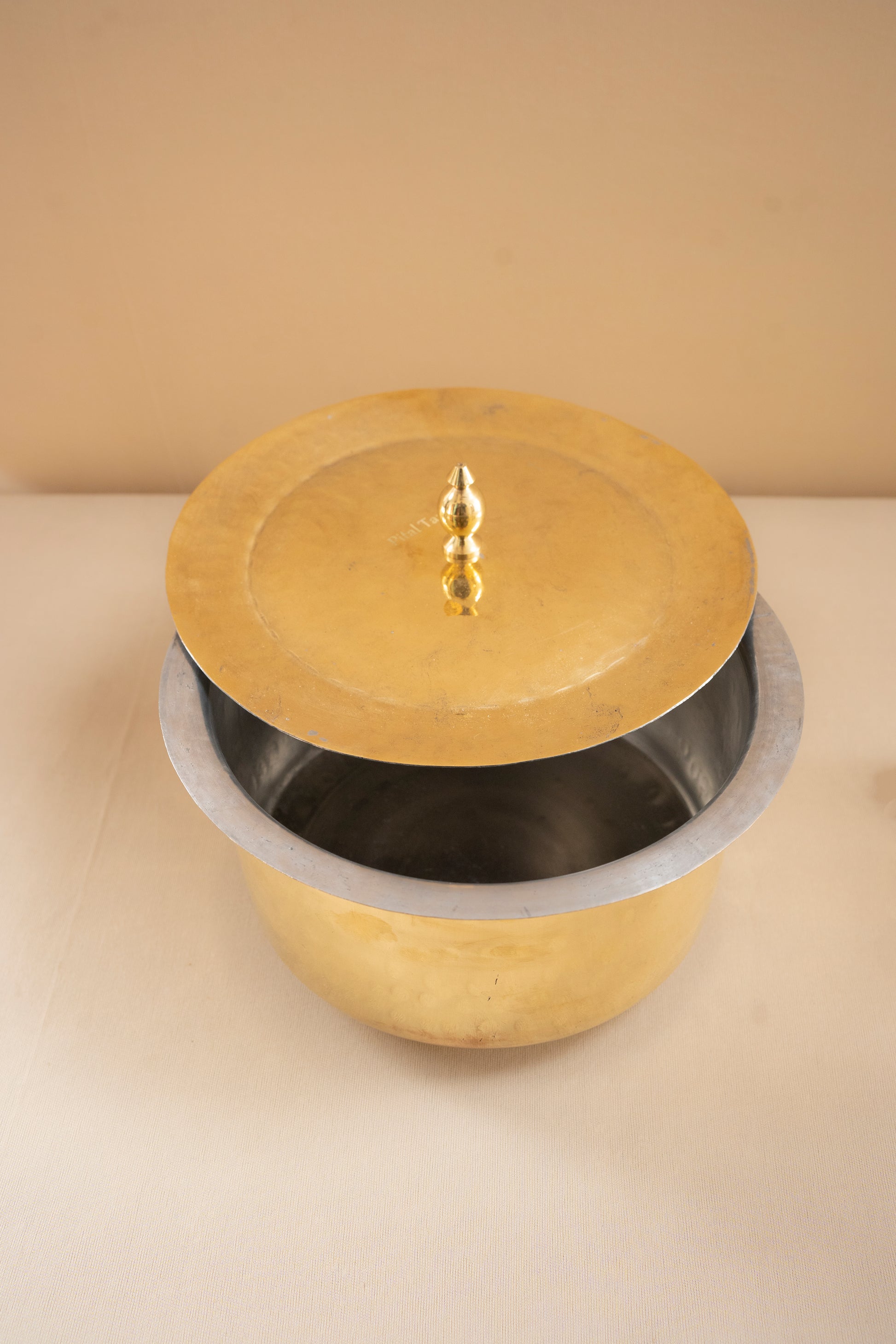 Brass pot with a lid on a beige background