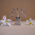 Decorative silver tree sculpture with white flowers on a beige background