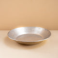 Silver bowl on a beige surface with a beige background