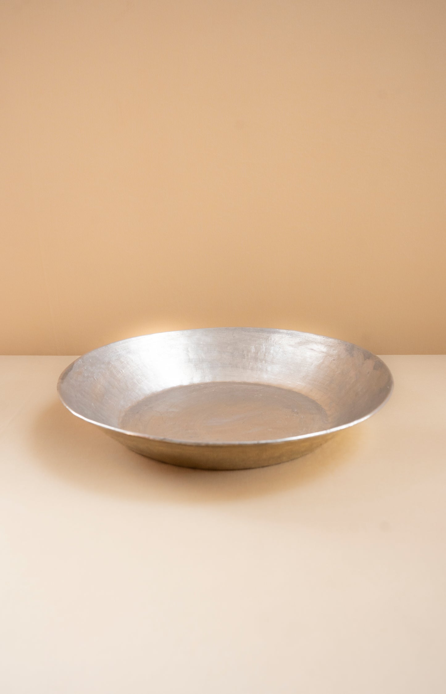 Silver bowl on a beige surface with a beige background