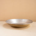 Silver bowl on a beige surface with a beige background