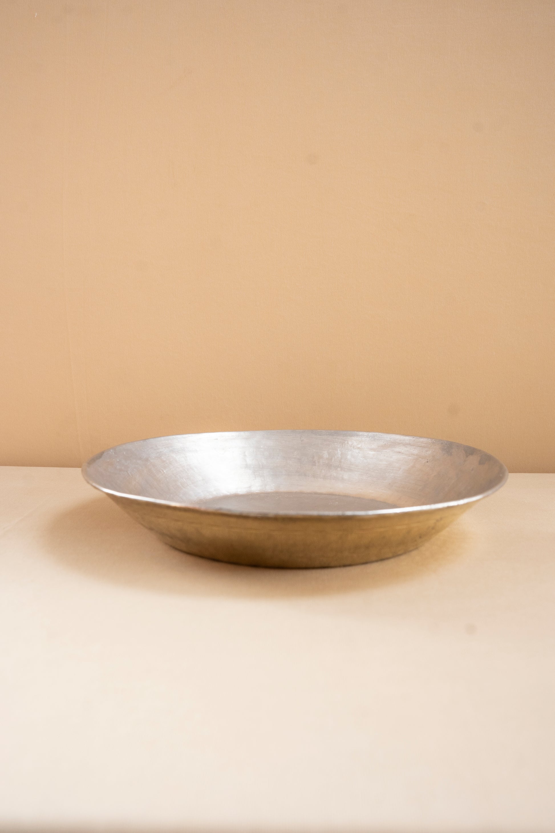 Silver bowl on a beige surface with a beige background