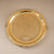 Decorative gold tray with intricate patterns on a beige background