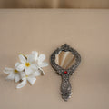 Decorative hand mirror with floral arrangement on a beige background