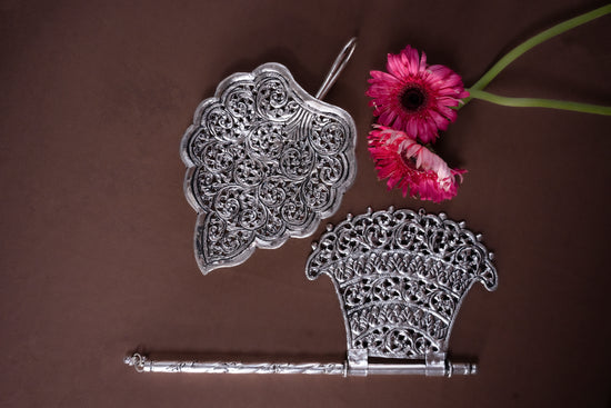 Decorative silver objects with a pink flower on a brown background