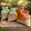 Three decorative bags with pom-poms on a stone surface with a garden background