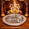Decorative setup with a statue of Ganesha on an ornate wooden platform with flowers and candles.