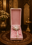 Decorative item in a pink box on a ornate table with floral and candle background