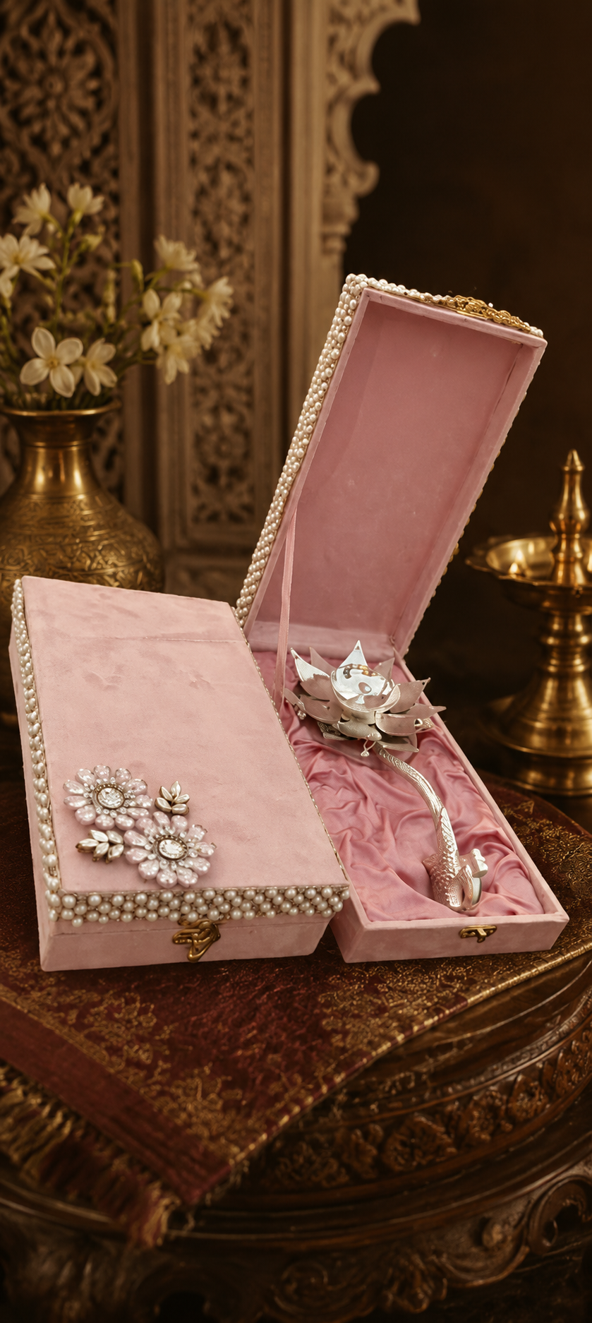 Pink jewelry box with silver jewelry on a decorative surface