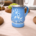 Blue ceramic mug with floral design on a tablecloth-covered table.