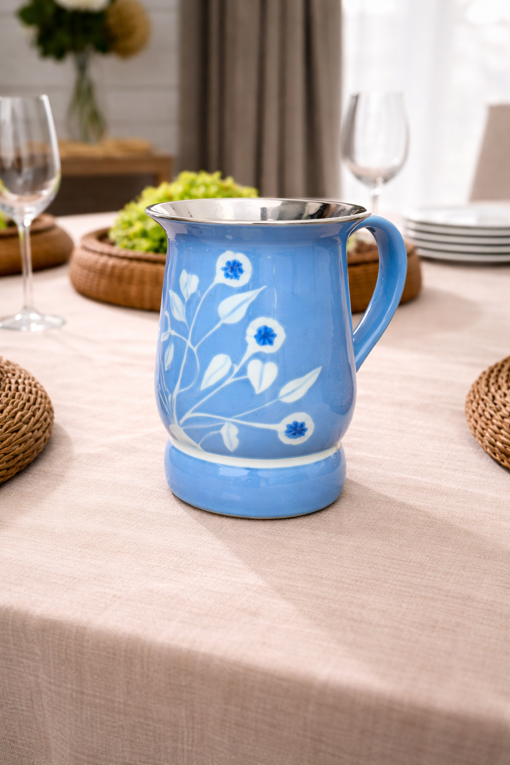 Blue ceramic mug with floral design on a tablecloth-covered table.
