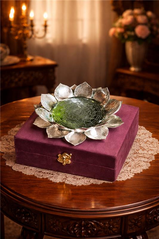 Decorative item with silver lotus design on a purple box on a wooden table.