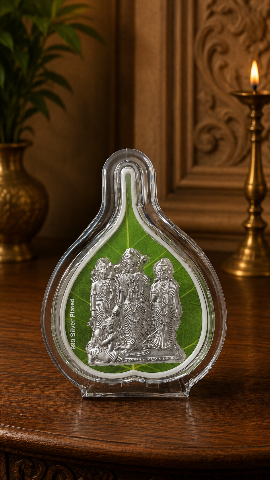 Decorative item with silver figures on a green background, placed on a wooden surface.