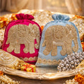 Two decorative bags with elephant designs on a tray with pearls and flowers.