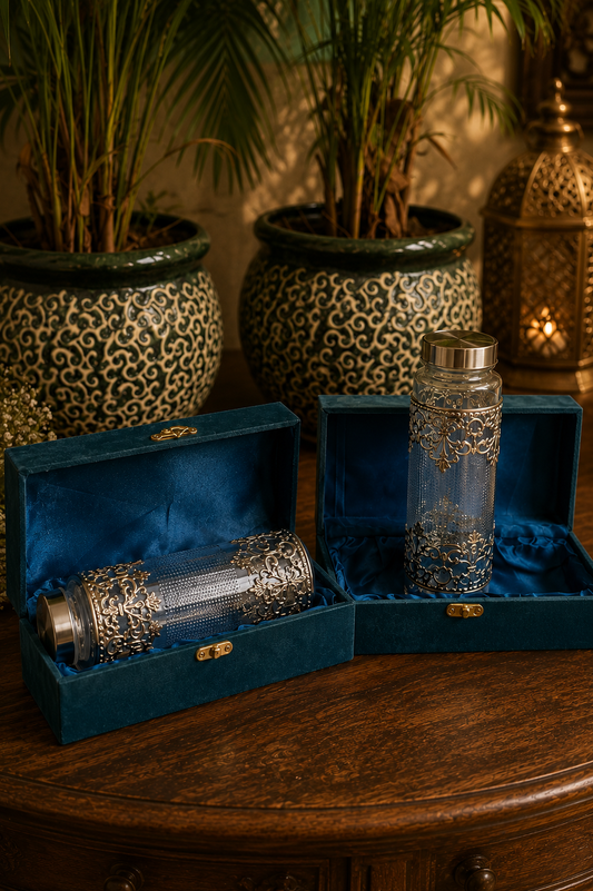 Decorative glass bottles with silver embellishments in blue velvet boxes on a wooden surface.