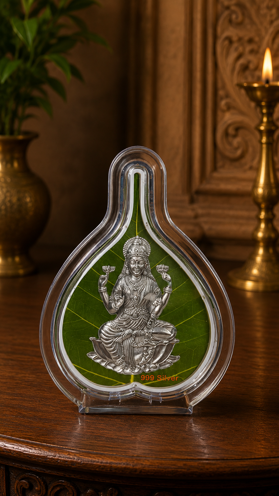 Decorative item with a seated figure on a green leaf in a clear teardrop-shaped frame on a wooden surface.