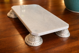 Marble tray with decorative silver feet on a wooden surface