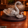 Silver swan sculpture on a dark base with a warm background