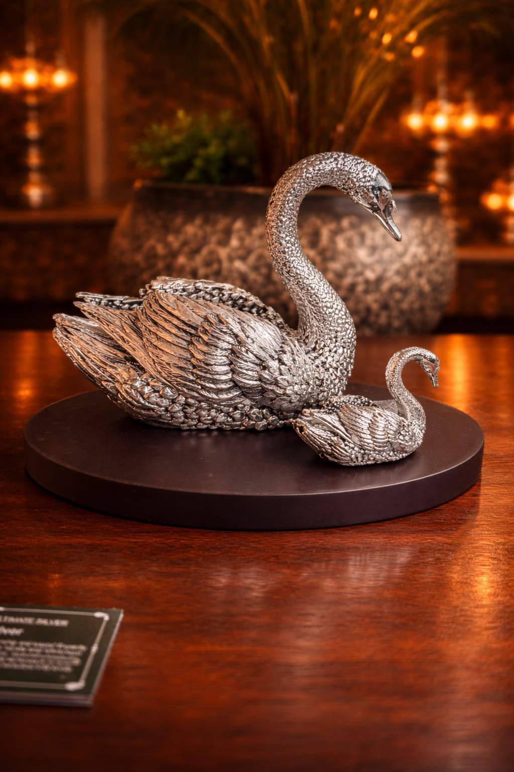 Silver swan sculpture on a dark base with a warm background