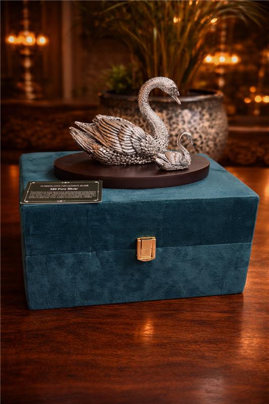 Decorative silver swan sculpture on a blue velvet box with a blurred background