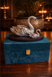 Decorative swan sculpture on a blue box with a warm background