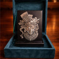Decorative mask in a blue velvet box on a wooden surface with blurred candles in the background