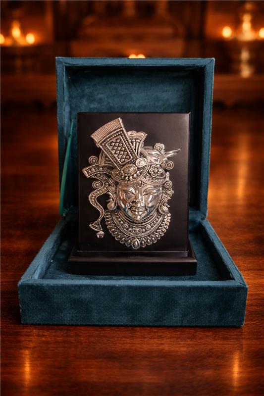 Decorative mask in a blue velvet box on a wooden surface with blurred candles in the background