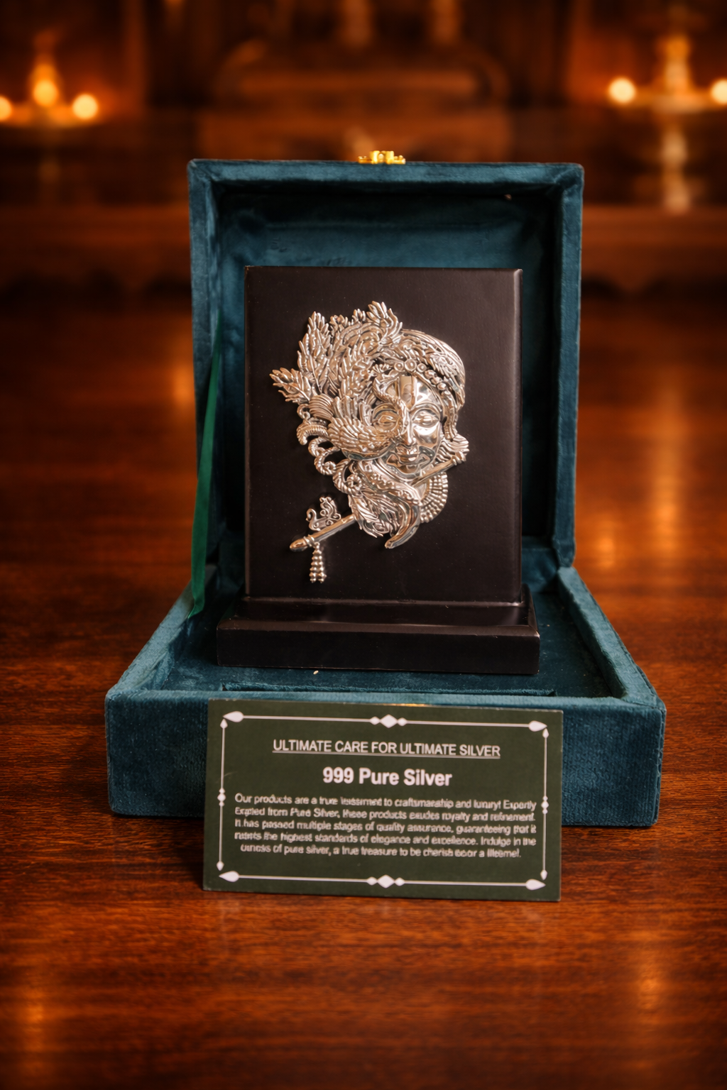 Silver brooch in a green velvet box on a wooden surface with candles in the background