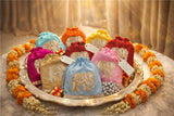 Decorative pouches with colorful fabric and gold embroidery on a decorative tray.