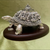 Decorative silver turtle figurine on a wooden base against a green background