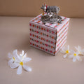 Decorative box with floral patterns and a small decorative item on a beige surface with flowers.