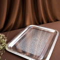 Silver decorative tray on a brown fabric background