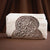 Decorative metal napkin holder with folded white napkins on a brown background